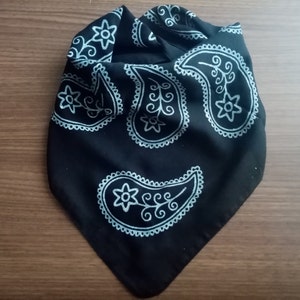 May include: Black bandana with a paisley pattern in white. The bandana is folded into a triangle shape.