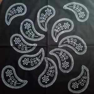 May include: Black fabric with a white paisley pattern. The paisley designs are arranged in a circular pattern.