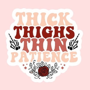 May include: A sticker with the text "THICK THIGHS THIN PATIENCE" in shades of red and peach. The design includes two black skeleton hands giving the middle finger and a floral accent at the bottom. The background is light pink.