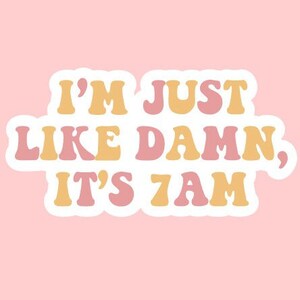May include: A sticker with a retro font design that reads "I'm just like damn, it's 7am". The sticker has a white outline and is on a pink background.