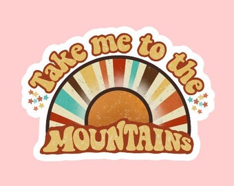 May include: A retro-style sticker with a sunburst design and the text "Take me to the mountains". The sticker is white with a brown, orange, yellow, blue, and red sunburst design. The text is in a brown, orange, and yellow font.
