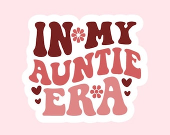 May include: A sticker with the text "In My Auntie Era" in a retro font with pink and brown colors and small flower and heart accents.