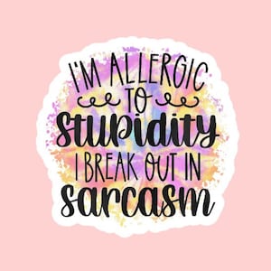May include: A white sticker with the text "I'M ALLERGIC TO STUPIDITY I BREAK OUT IN SARCASM" in black script. The text is set against a colorful watercolor background of pink, yellow, and blue hues, on a pink background.