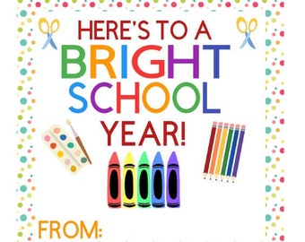 Puede incluir: Una etiqueta de regalo imprimible colorida con el texto "Here's to a Bright School Year!" rodeada por un borde de puntos coloridos. La etiqueta también incluye imágenes de tijeras, crayones, pinceles y una paleta de pintura.