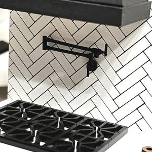 May include: A black, articulated pot filler faucet mounted on a white herringbone tile backsplash. The image also shows a black cooktop grate and a black countertop.