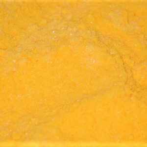 May include: A close-up of a bright yellow powder, likely turmeric or curry powder.