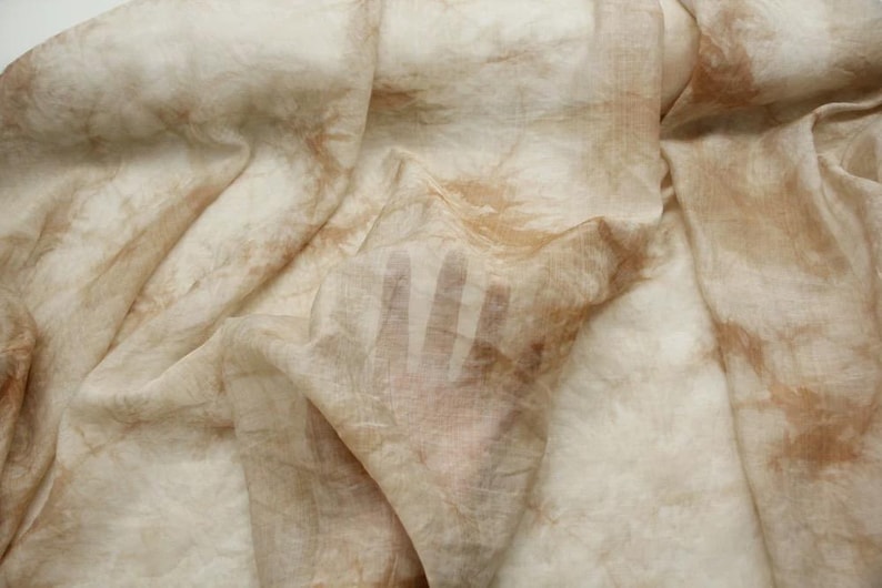 May include: A light brown fabric with a handprint pattern. The fabric is sheer and has a soft, flowing texture.