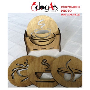 May include: Set of four wooden coasters with a coffee cup design. Each coaster features a different design of a coffee cup with steam rising from it. The coasters are arranged in a square shape with a wooden holder in the center. The holder has a cutout design of a coffee cup with steam rising from it. The text "CUSTOMER'S PHOTO NOT FOR SALE" is visible in the top right corner of the image.