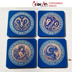 May include: Four blue square coasters with a gold zodiac symbol on each. The symbols are Aries, Leo, Virgo, and Capricorn.