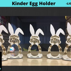 May include: Five wooden bunny-shaped Kinder egg holders with personalized names and the text "Happy Easter".