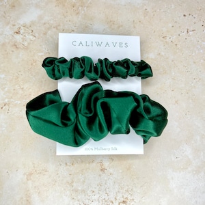 May include: Two green silk scrunchies, one larger and one smaller, on a white card with the text "CALIWAVES" and "100% Mulberry Silk".