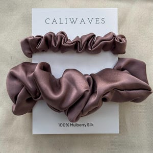 May include: Two brown satin scrunchies on a white card with the text "CALIWAVES" and "100% Mulberry Silk".
