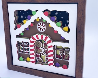 May include: A 3D gingerbread house with candy cane trim and a candy cane archway. The house is decorated with colorful lights and stars. Two gingerbread people are standing in the doorway.