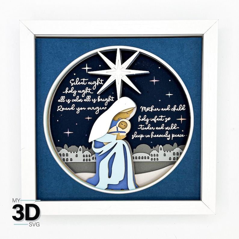 May include: A white framed 3D wood carving of the nativity scene with a blue background. The carving features Mary holding baby Jesus, a star, and the text "Silent night holy night all is calm all is bright Round you virgin Mother and child holy infant so tender and mild sleep in heavenly peace".