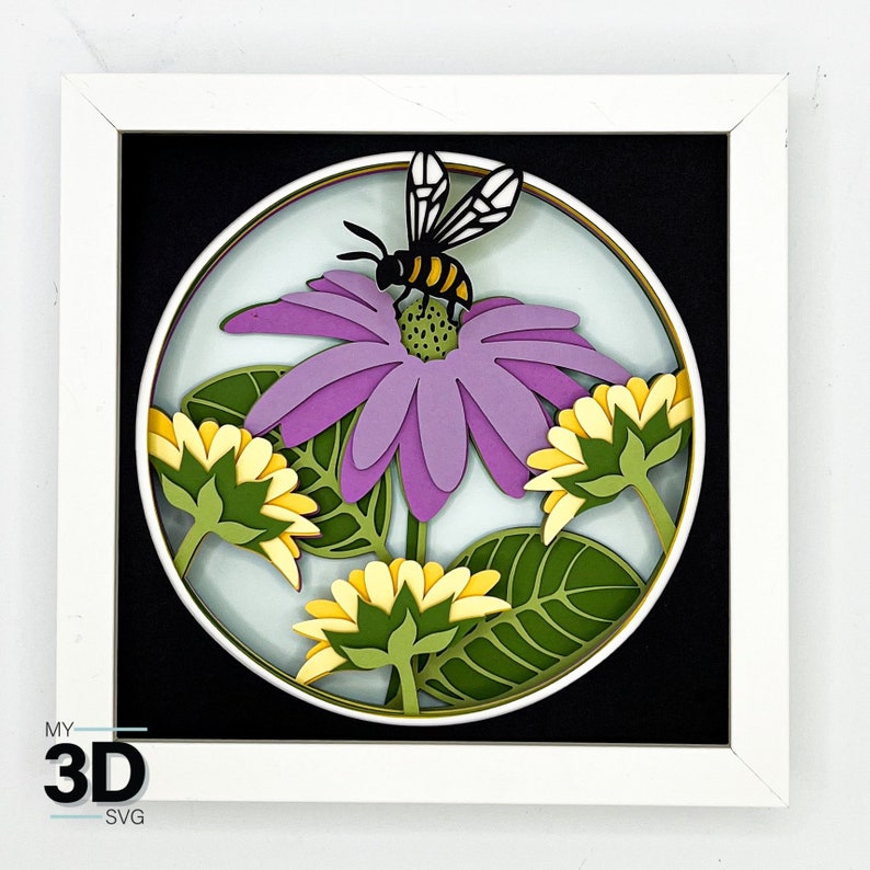 May include: A white frame with a black background and a circular cutout featuring a purple flower with a yellow and black bee on top. The flower is surrounded by smaller yellow flowers and green leaves.