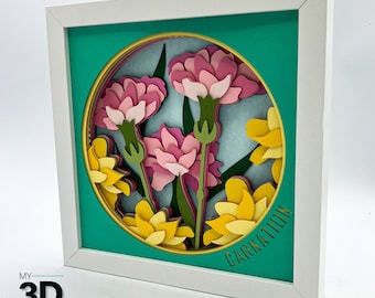 Puede incluir: Un marco blanco con un paspartú turquesa y un recorte redondo que presenta un diseño de arte de papel en capas de claveles rosas y flores amarillas. El texto "Carnation" está escrito en letras doradas en la parte inferior del recorte.