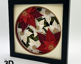 May include: A black framed picture with a white background and a circular design of red and white poinsettia flowers and green leaves.