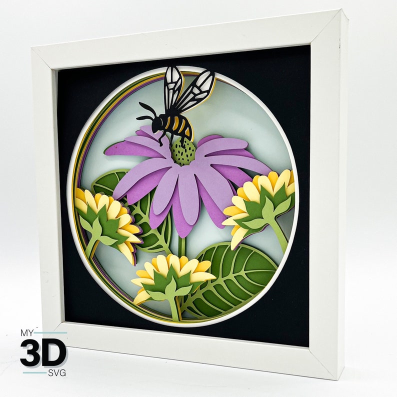 May include: A 3D paper craft of a purple flower with a yellow and black bee on it. The flower is surrounded by other flowers and leaves. The craft is framed in a white frame.