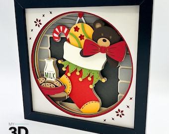 May include: A 3D papercraft scene of a fireplace with a stocking hanging from the mantle. The stocking is filled with a teddy bear wearing a red bow tie, a candy cane, and a yellow ball with red stars. A bottle of milk and cookies are on a table in front of the fireplace.