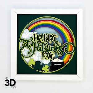 May include: A white frame with a green background and a circle in the center. The circle has a rainbow, clouds, shamrocks, and the text "Happy St. Patrick's Day".