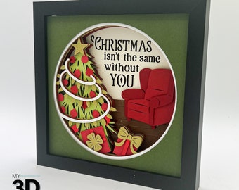 May include: A framed 3D papercraft design with a Christmas tree, a red armchair, and the text "Christmas isn't the same without YOU".