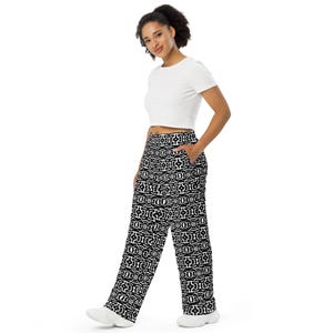 Könnte beinhalten: Ein weißes kurzärmeliges bauchfreies Oberteil kombiniert mit einer weit geschnittenen Hose mit sich wiederholendem schwarz-weißem geometrischem Muster. Die Hose hat eine hohe Taille, eine lockere Passform und sichtbare Seitentaschen.