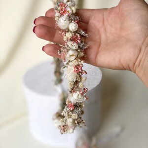 May include: A delicate floral crown made with dried flowers in shades of white and pink. The crown is made with small, delicate flowers and is perfect for a special occasion.