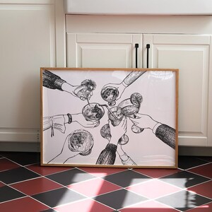 Op de afbeelding: Een zwart-witte illustratie van mensen die hun glazen heffen voor een toast. De illustratie is ingelijst in een licht houten lijst en hangt aan een witte muur.