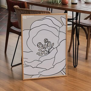 Pu&ograve; includere: Un disegno a tratto in bianco e nero di un grande fiore con un centro dettagliato, incorniciato da una cornice in legno marrone chiaro. La stampa &egrave; su sfondo bianco.