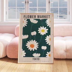 May include: A framed poster with a green background and white daisies. The poster says "FLOWER MARKET TOKYO" at the top and "BOTANIC COLLECTIONS NO. V GALLERY FOR ART" at the bottom.