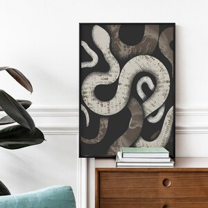 May include: A black and white abstract print of snakes intertwined, framed in a black frame. The print is hanging on a white wall above a wooden dresser.