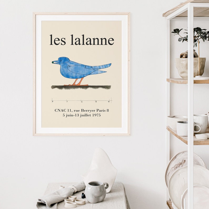 May include: A framed poster with a blue bird illustration and the text "les lalanne" in black. The poster also includes the text "CNAC 11, rue Berryer Paris 8 5 juin-13 juillet 1975".