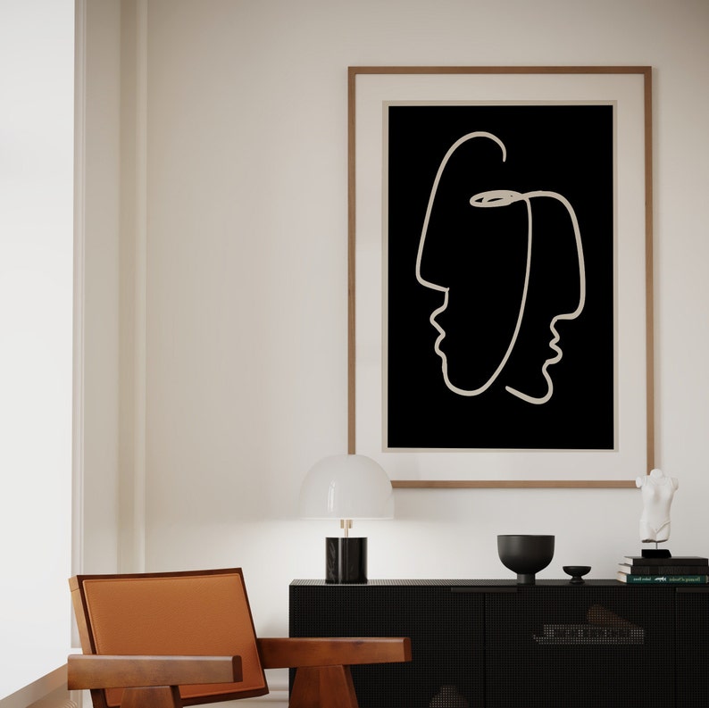 Puede incluir: Una impresi&oacute;n en blanco y negro de dos caras, una dentro de la otra, en un estilo simple y moderno. La impresi&oacute;n est&aacute; enmarcada en un marco de madera clara y cuelga de una pared blanca sobre una mesa auxiliar negra.