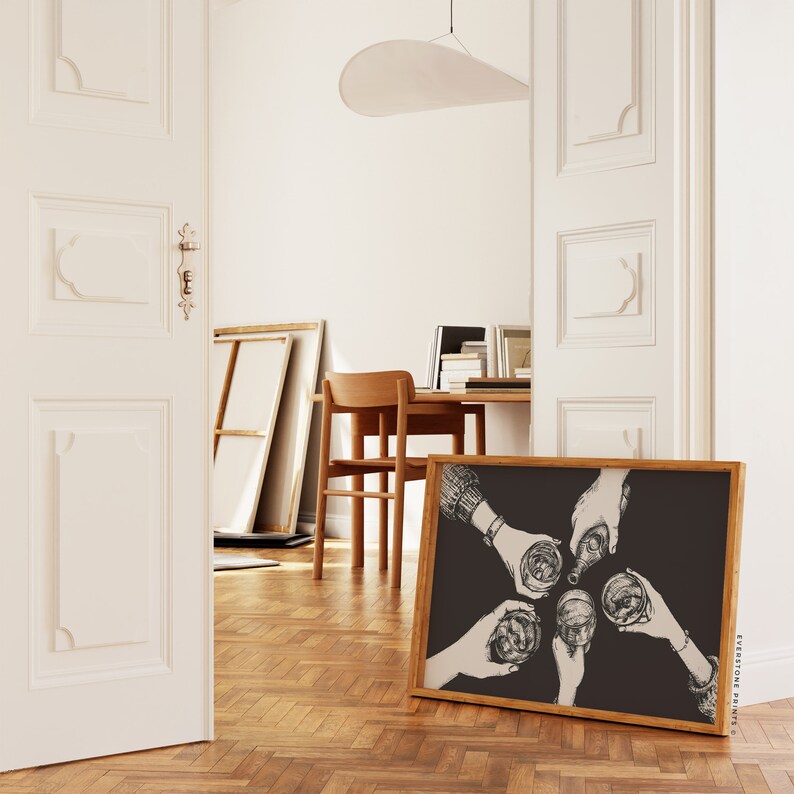 May include: Black and white illustration of four hands raising glasses in a toast. The illustration is framed in a wooden frame and is hanging on a wall.
