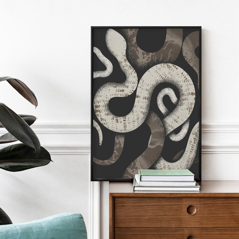 May include: A black and white abstract print of snakes intertwined, framed in a black frame. The print is hanging on a white wall above a wooden dresser.