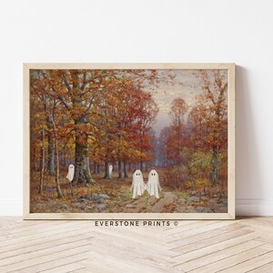 May include: A vintage painting of a forest scene with fall foliage in shades of red, orange, and yellow. Three white ghosts are walking on a path in the woods. The painting is framed in a light wood frame. EVERSTONE PRINTS &copy;