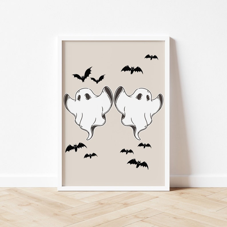 May include: A printable wall art design featuring two white ghosts with black eyes and a beige background.  The ghosts are facing each other and have their arms raised.  There are several black bats scattered around the ghosts.