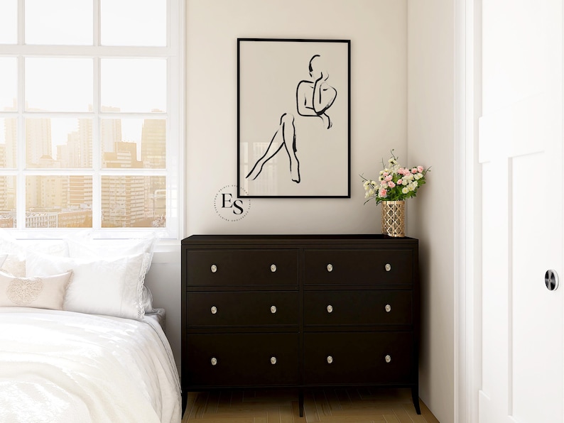 Pu&ograve; includere: Un disegno in bianco e nero di una persona seduta con le gambe incrociate. Il disegno &egrave; incorniciato e appeso a una parete bianca sopra una cassettiera marrone scuro con sei cassetti.