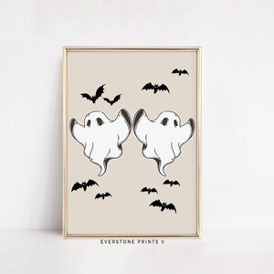 May include: A printable digital download featuring two white ghosts with black eyes and a beige background.  The ghosts are facing each other with their arms raised.  There are several black bats scattered around the ghosts.  The text "EVERSTONE PRINTS &copy;" is at the bottom of the image.