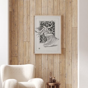 May include: A black and white line drawing of a woman dancing in a forest setting. The drawing is framed and hanging on a wooden wall.