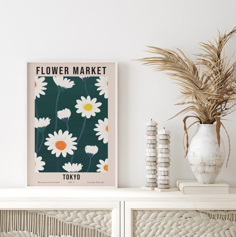 May include: A framed poster with a floral design. The poster features a white daisy pattern on a dark green background. The text "FLOWER MARKET TOKYO" is printed on the poster.