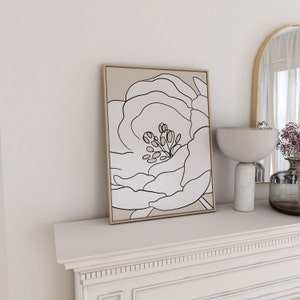 Pu&ograve; includere: Una stampa incorniciata di un disegno in bianco e nero di un fiore su sfondo beige.