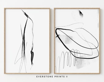 May include: Two black and white abstract art prints in wooden frames. The prints feature simple line drawings and black ink splatters on a white background.