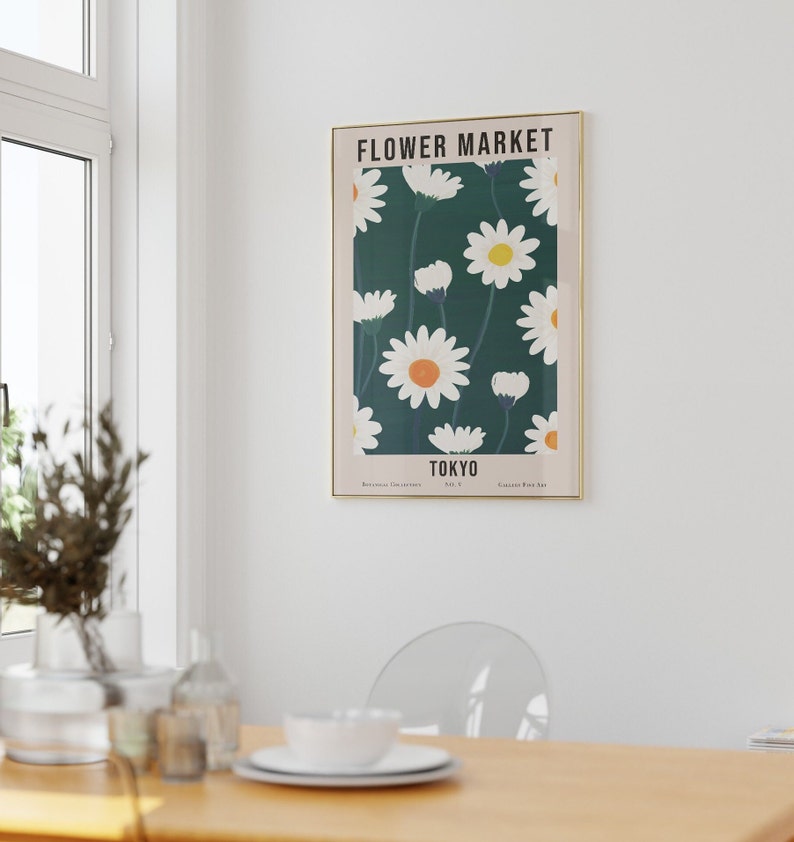 May include: A framed poster with a green background and white daisies with yellow centers. The poster says "FLOWER MARKET" and "TOKYO" in a white sans-serif font.