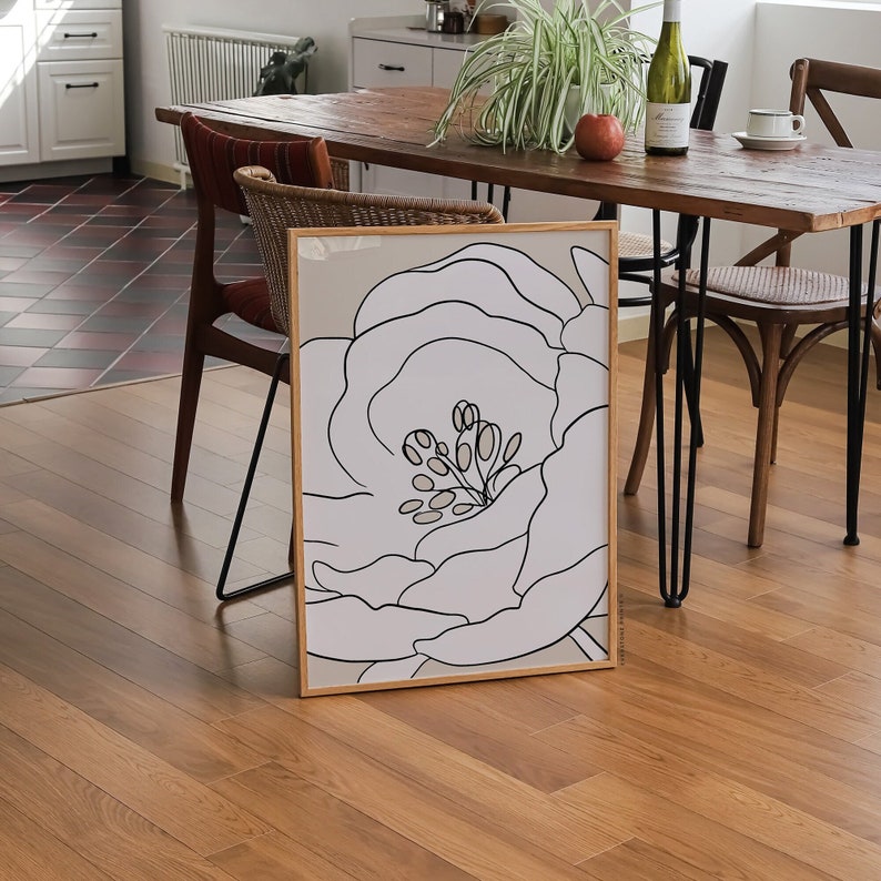 Pu&ograve; includere: Un disegno a tratto in bianco e nero di un grande fiore con un centro dettagliato, incorniciato da una cornice in legno marrone chiaro. La stampa &egrave; su sfondo bianco.