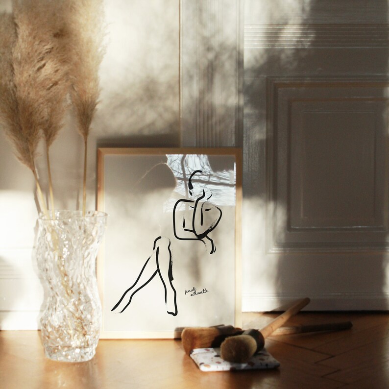 Pu&ograve; includere: Un disegno in bianco e nero di una silhouette di una persona incorniciato. Il disegno &egrave; su sfondo bianco e la cornice &egrave; in legno chiaro. Il testo "female silhouette" &egrave; scritto in nero nella parte inferiore del disegno.