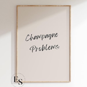 May include: A framed print with the text "Champagne Problems" in black cursive font on a light beige background.