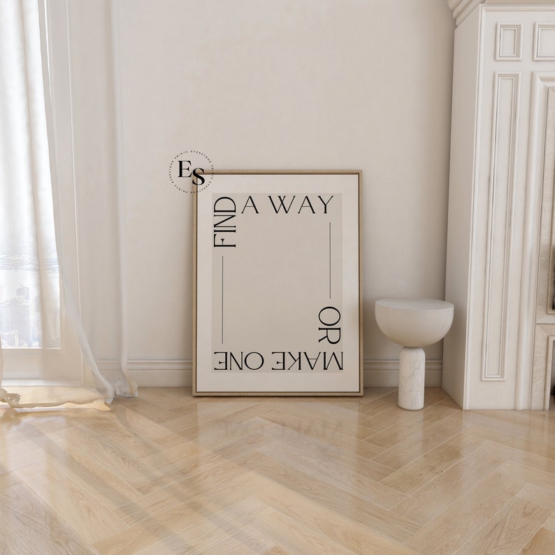 May include: A beige poster with black text that reads "FIND A WAY OR MAKE ONE". The poster is hanging on a white wall in a room with a white fireplace and a white side table.