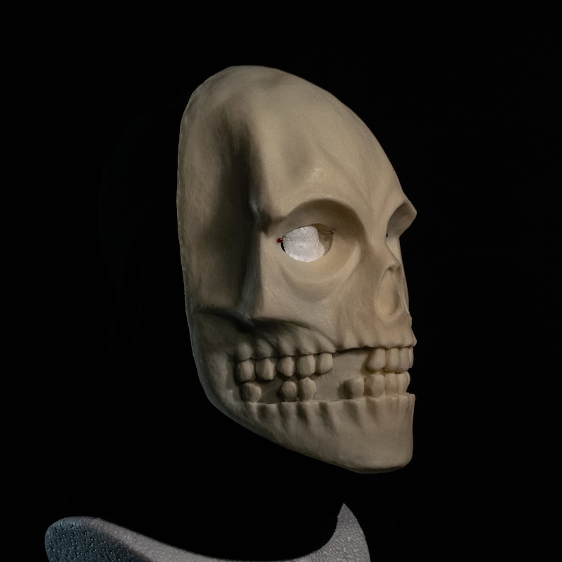 May include: A white skull mask with a single eye socket. The mask is made of a smooth, pliable material and has a realistic appearance.