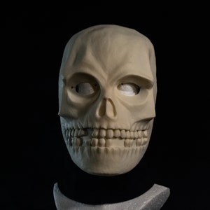 May include: A white skull mask with a detailed, realistic design. The mask has a sculpted jawline, teeth, and eye sockets.